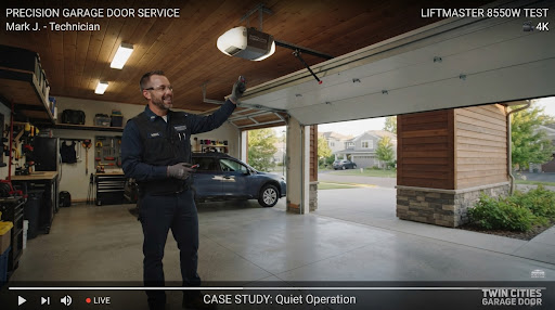 Technician in an open garage pointing at a newly installed belt-drive opener
