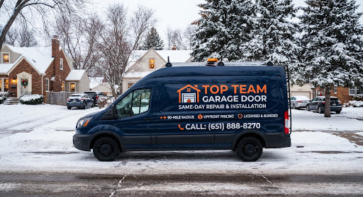 Top Team Garage Door service van parked on a snowy Minneapolis residential street lined with older brick and stucco homes