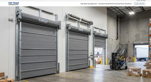 Three gray insulated sectional steel overhead doors on heavy track inside a warehouse, with a forklift and pallets on the floor